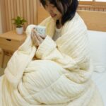 ผู้หญิงห่อตัวด้วยผ้าห่ม Marshmallow ในมือถือแก้วชาอุ่น ๆ อยู่ด้วย