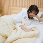 ผู้หญิงห่มผ้าห่ม Marshmallow อยู่บนที่นอน