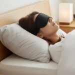 ผู้หญิงนอนหลับอยู่บนเตียงและใช้ผ้าปิดตา Carbon eye mask